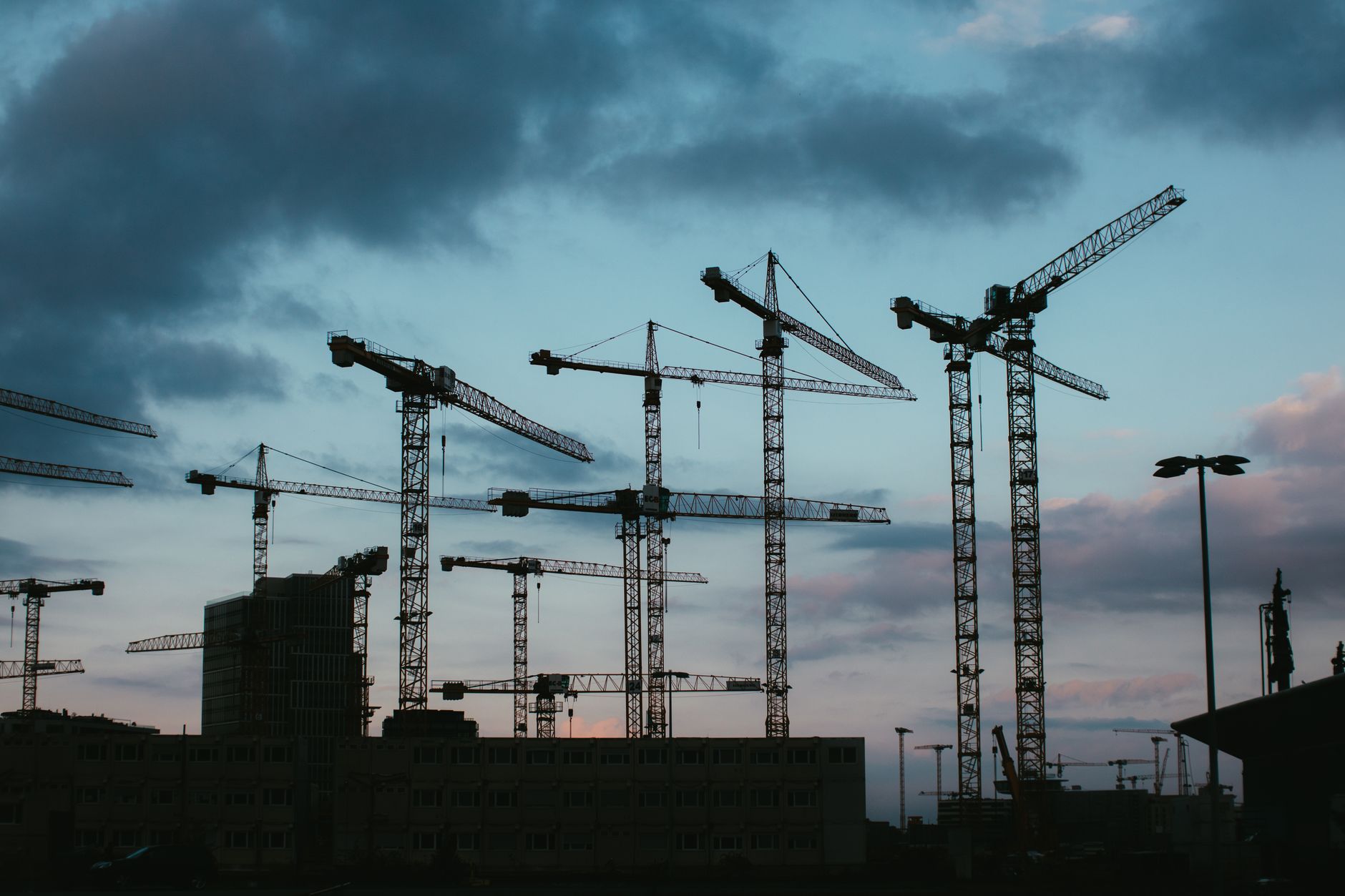 Construction cranes against an evening sky