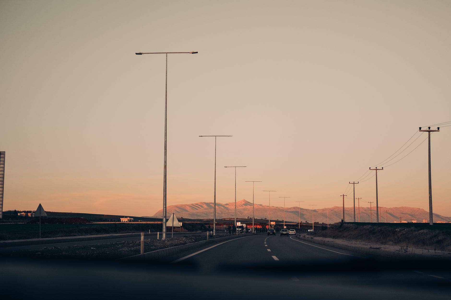 An empty highway at dusk under street lights