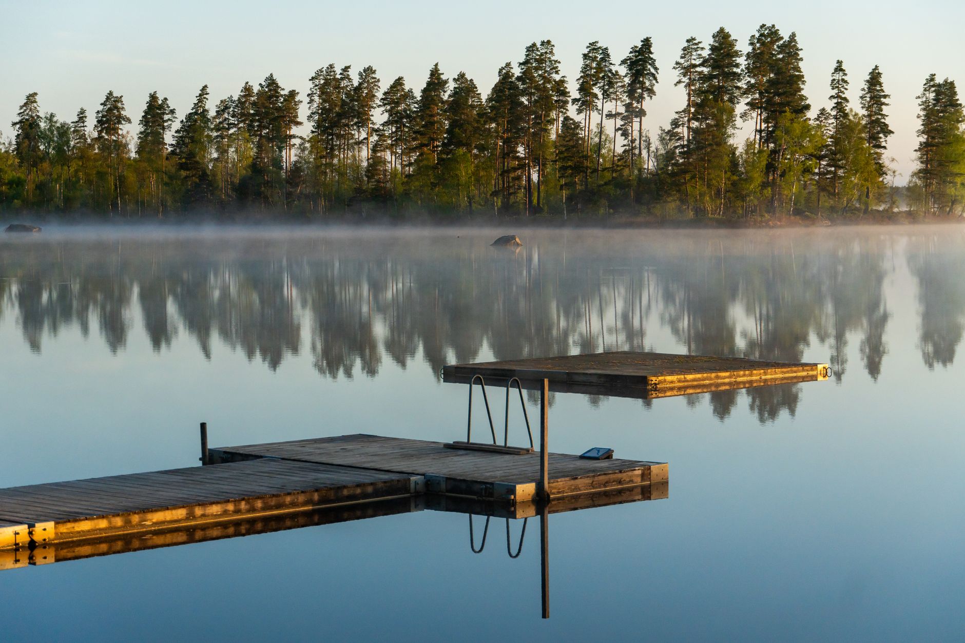 A wooden dock on a still lake at sunrise