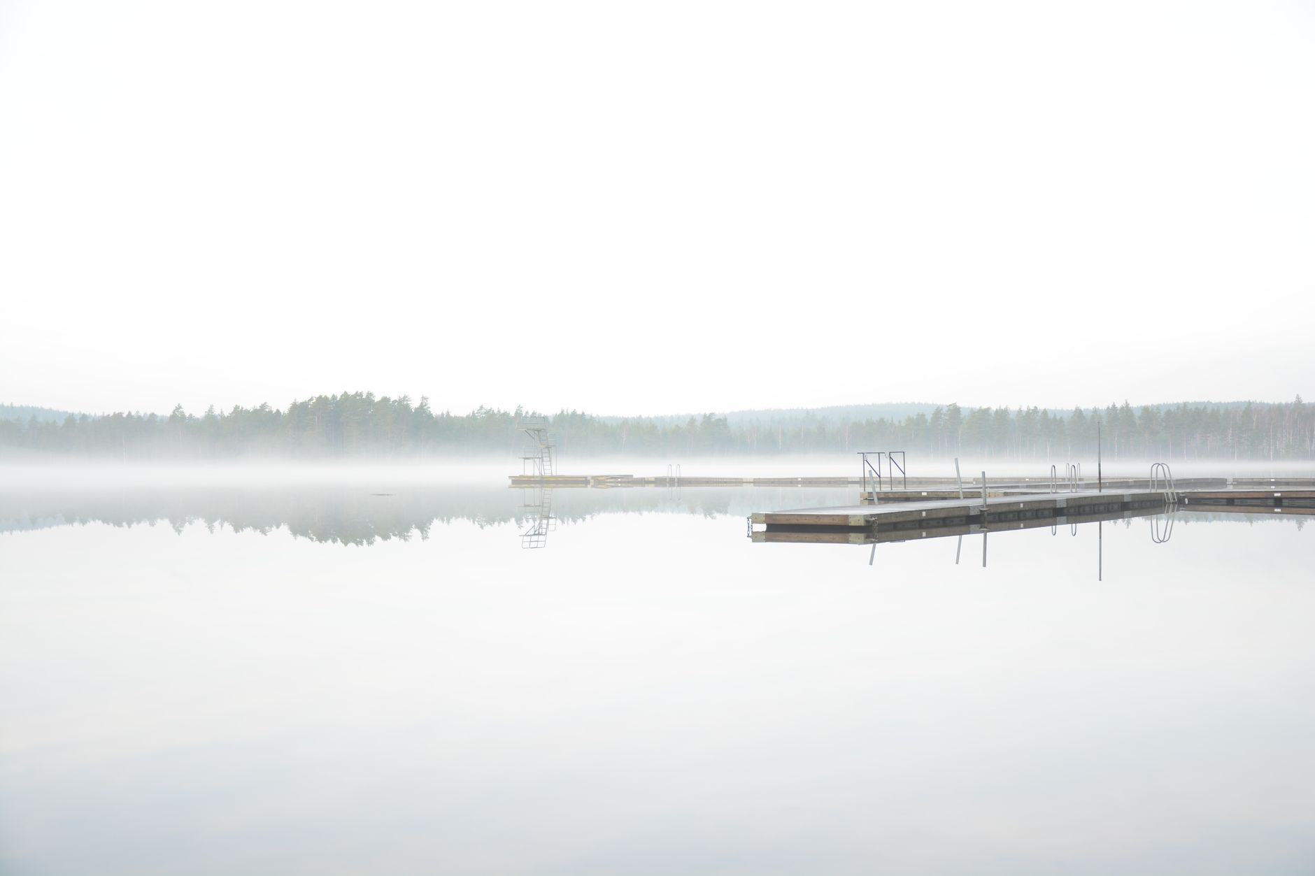 Mist over a calm lake with a dock in the distance