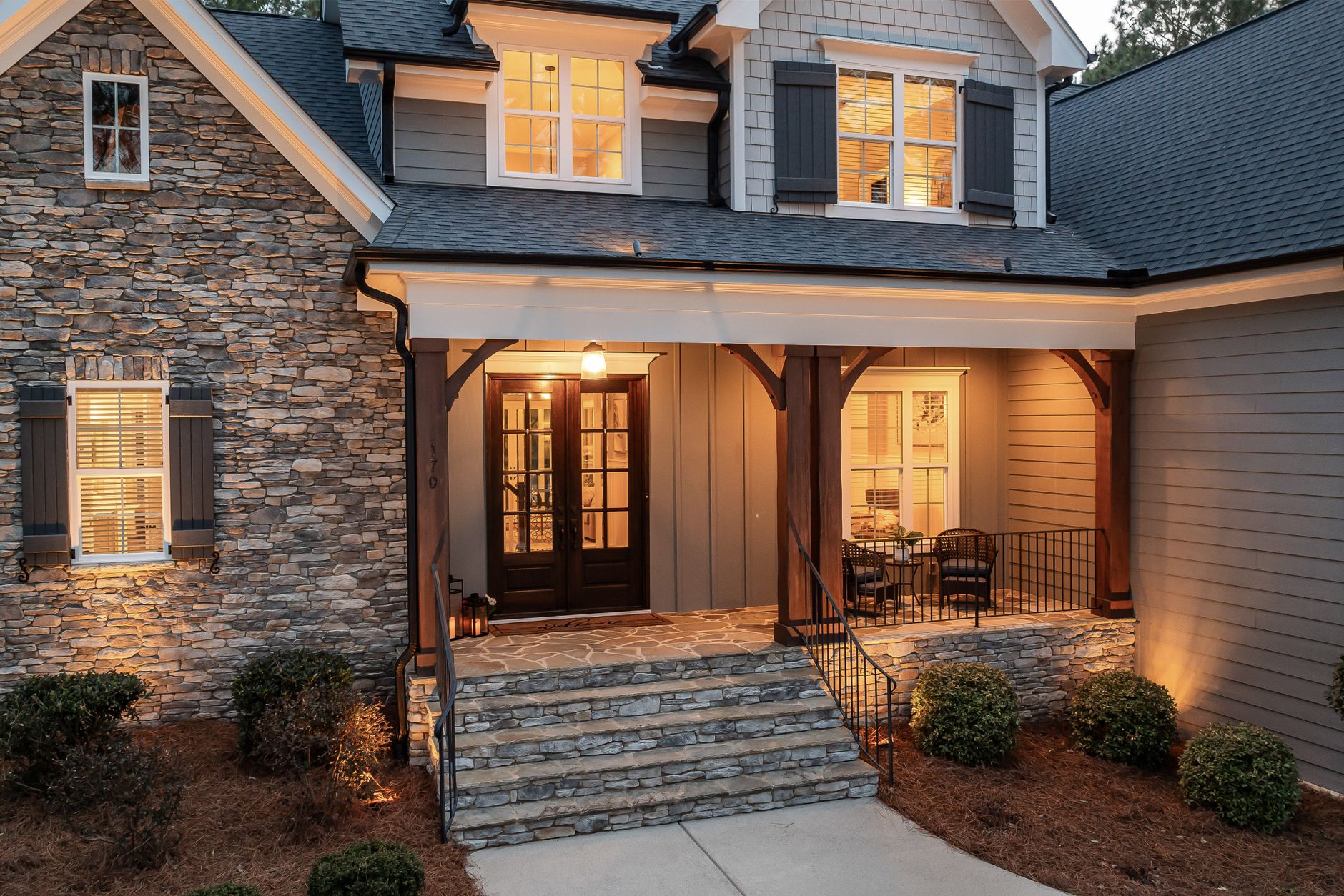 A stone house with its porch light on at dusk